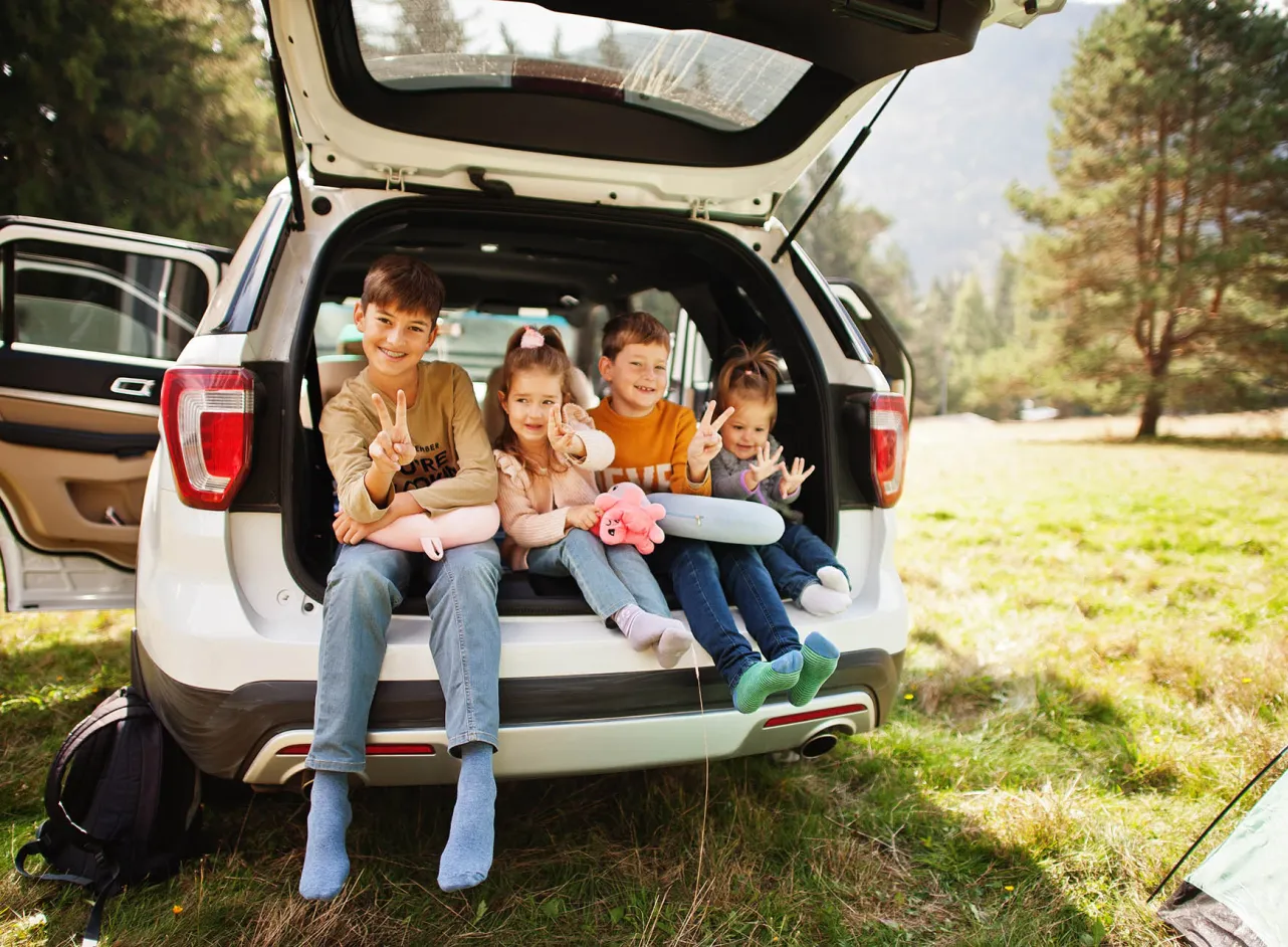 four smiling children in car boot 
